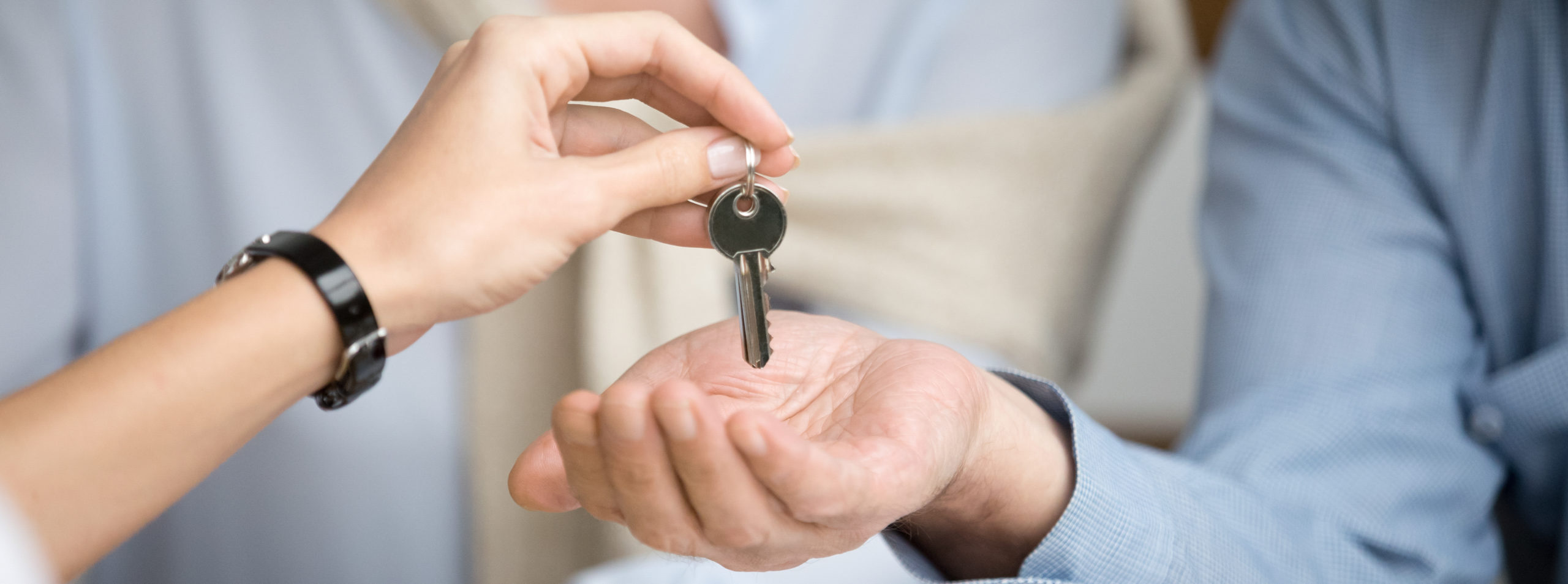 a person passing to keys to couple after selling a house to them