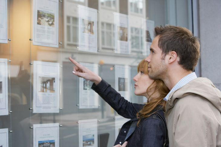 two people looking in estate agent window