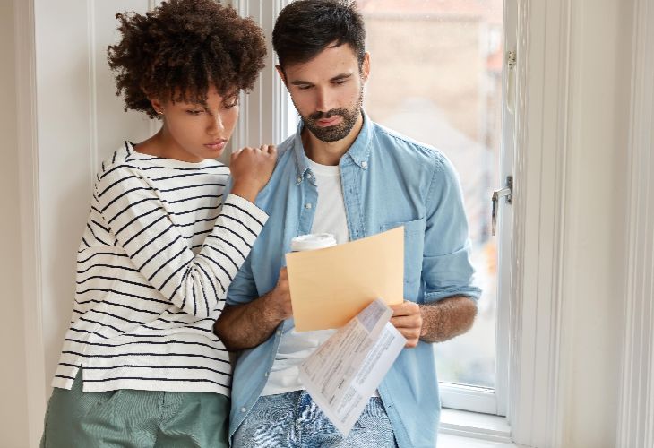 Smiling couple reviewing rental agreement paperwork at home